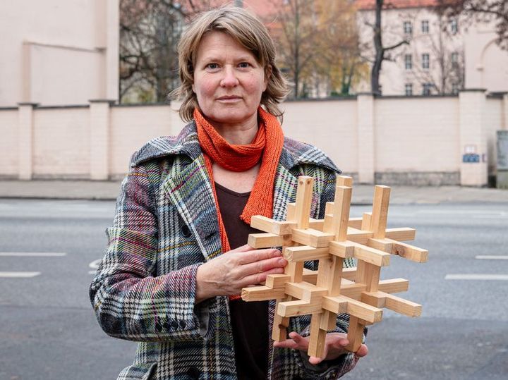 Angelika Drescher vom Bauhaus der Erde hält ein Holzbaumodell in der Hand.