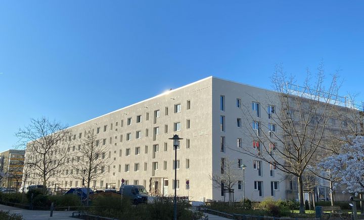 Blick auf eine sanierte Wohnhausfassade im Hertha-Thiele-Weg. Die Fassade ist hell und modern.