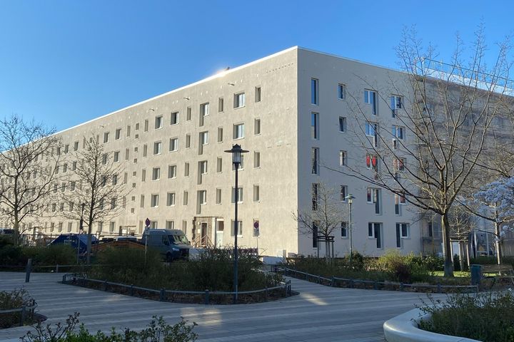 Blick auf eine sanierte Wohnhausfassade im Hertha-Thiele-Weg. Die Fassade ist hell und modern.