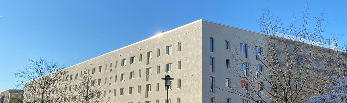 Blick auf eine sanierte Wohnhausfassade im Hertha-Thiele-Weg. Die Fassade ist hell und modern.