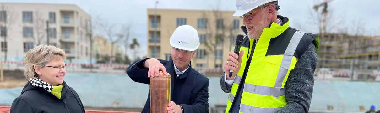 Angela Brandenburg, Mike Schubert und Bert Nicke befüllen die Zeitkapsel an der Baustelle im Bornstedter Feld.