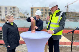Angela Brandenburg, Mike Schubert und Bert Nicke befüllen die Zeitkapsel an der Baustelle im Bornstedter Feld.