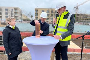 Angela Brandenburg, Mike Schubert und Bert Nicke befüllen die Zeitkapsel an der Baustelle im Bornstedter Feld.