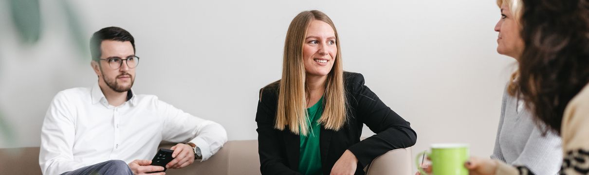 mehrere Personen sitzen sich gegenüber in einer Gesprächssituation