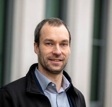 GEWOBA-Geschäftsführer Gregor Heilmann in schwarzer Jacke und blauem Hemd vor unscharfem Hintergrund
