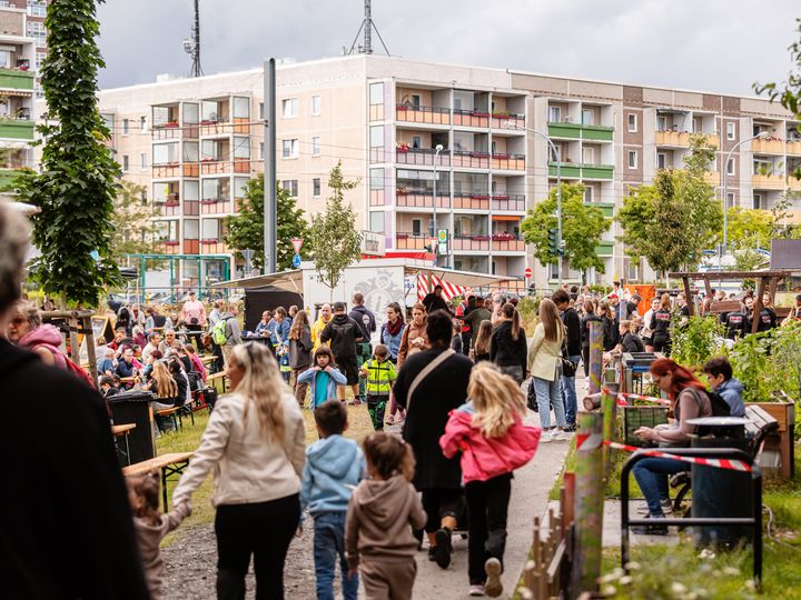 14. Gartenstadtfest im Quartier Besucherinnen und Besucher beim Gartenstadtfest auf einer Veranstaltungsfläche zwischen Wohngebäuden und Gemeinschaftsgärten.