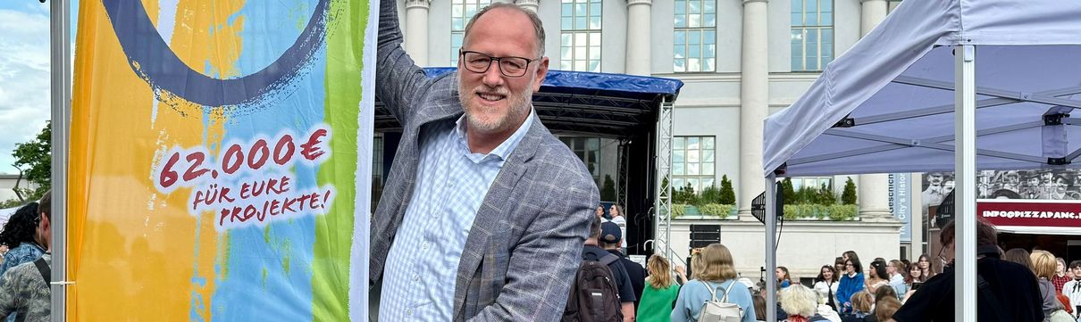 ProPotsdam-Geschäftsführer Bert Nicke steht vor einer Beachflag des Wettbewerbs ProPotsdam Gemeinsam FÜR Potsdam