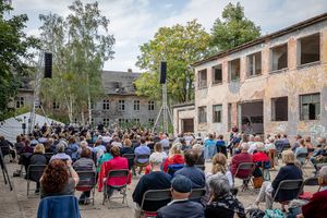 Viele Zuschauer hören ein Konzert von Musikern auf einer Freiluftbühne in Krampnitz.