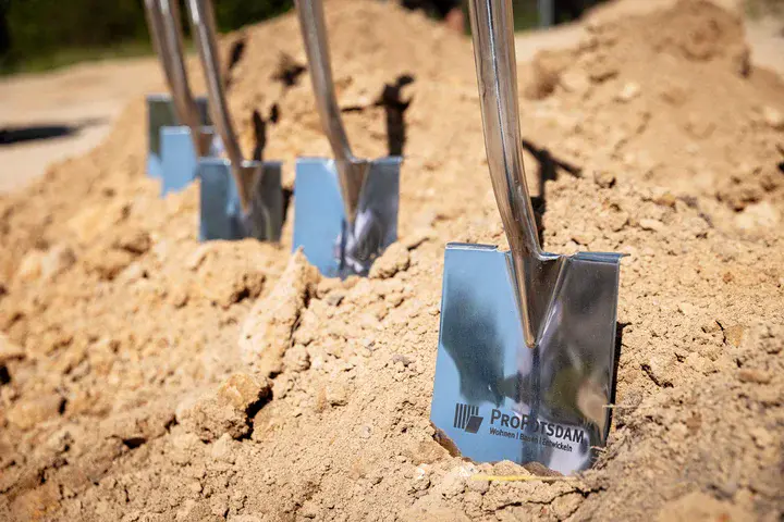 Mehrere glänzende Spaten mit ProPotsdam-Logo stecken für einen symbolischen Spatenstich in einem Sandhaufen.