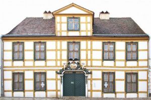 Ein zweistöckiges Wohnhaus mit Mittelgang, cremefarbener Fassade und Giebel 