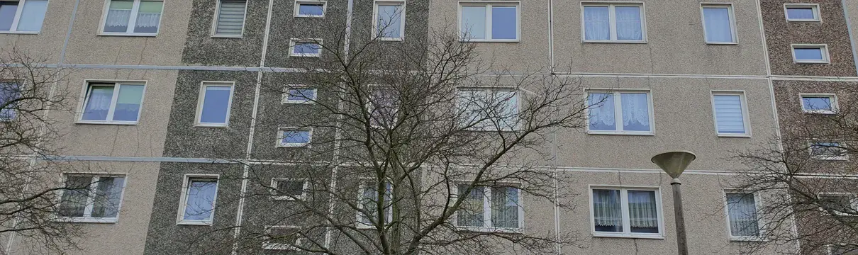 Graue Hausfassade eines 5 Geschossers.