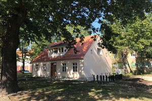 Das Bild zeigt das sanierte Heidehaus und Bäume.