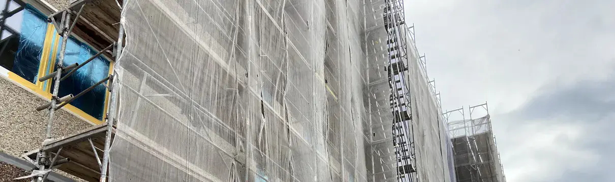 Ein Gebäude das mit einem Gerüst verkleidet ist und saniert wird.