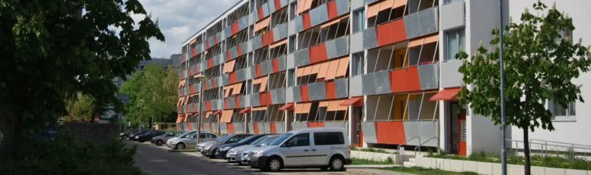 Sanierter, fünfstöciker Plattenbau mit rotfabrigen Balkonen