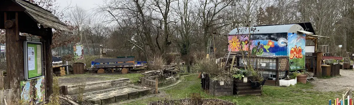 Garten mit einem buntbemalten Holzzaun und Gartenhaus.