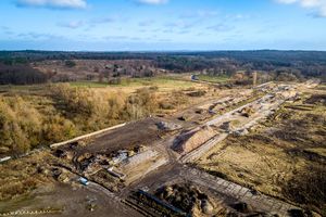 Im Vordergrund einige nach sandigen Baustellen aussehende Flächen, im Hintergrund eine Naturlandschaft. 