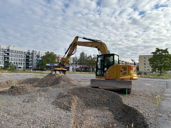 Rasterfelduntersuchung auf dem Neubaufeld Bagger bei einer Rasterfelduntersuchung auf einem künftigen Neubaufeld mit mehreren geöffneten Bodenprofilen.