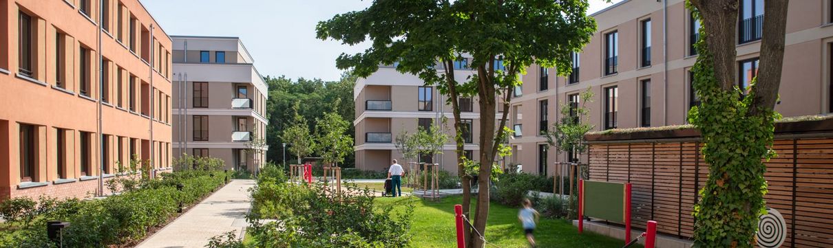 Das Foto zeigt das Bauprojekt der ProPotsdam in der Heinrich-Mann-Allee mit Häusern, Bäumen und Grünanlagen.