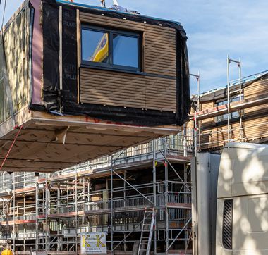 Gebäudeteil, der vor Baustelle mit Hilfe eines Krans in die Luft gehoben wird