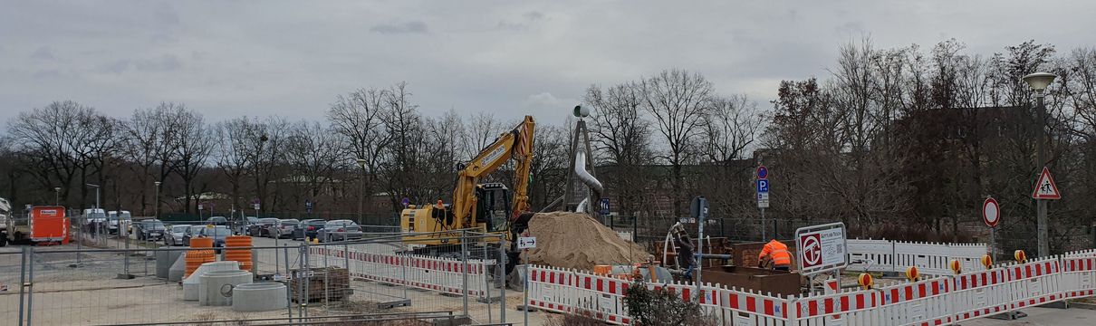 Baustelle mit blauen Leitungsarbeiten und Bauarbeite sowie Maschinen im Hintergrund