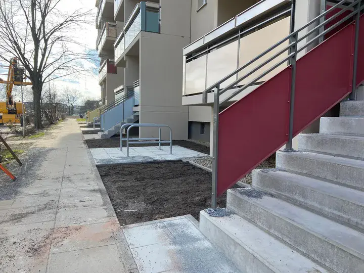 Außenbereich eines Wohngebäudes mit Treppen, neu angelegten Wegen und Fahrradständer.