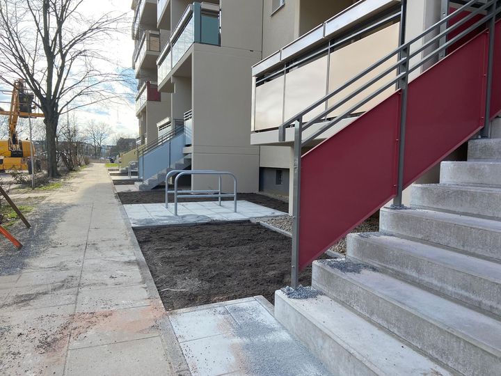 Außenbereich eines Wohngebäudes mit Treppen, neu angelegten Wegen und Fahrradständer.