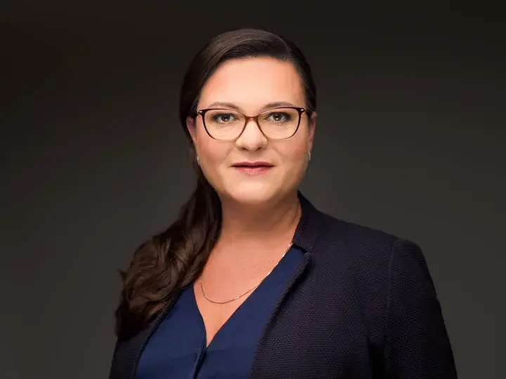 GEWOBA-Geschäftsführerin Bianca Künkel in schwarzem Jacket und blauer Bluse vor dunklem Hintergrund