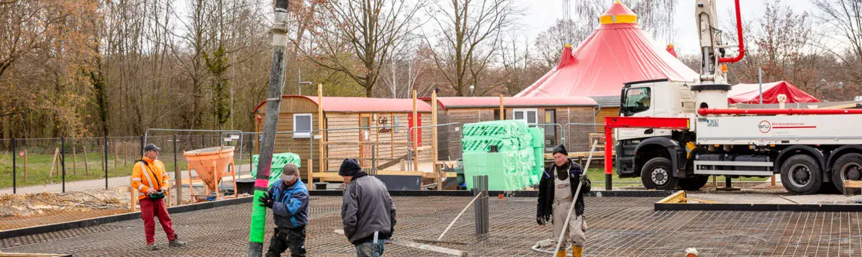Bauarbeiter arbeiten, im Hintergrund steht das Zelt des Circus Montelino.
