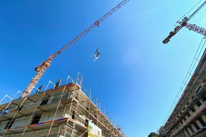 Baukräne und ein Richtkranz an einer Baustelle in der Heinrich-Mann-Allee