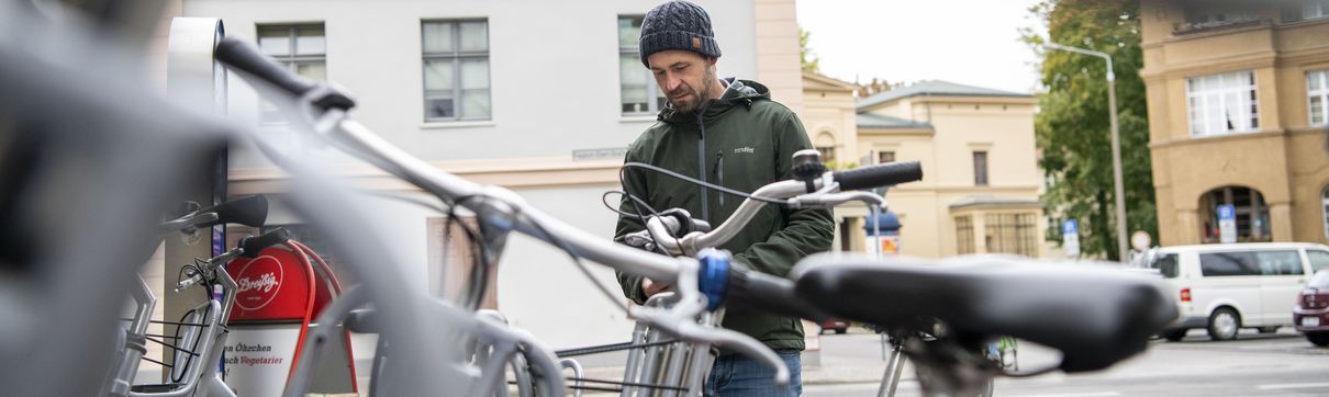 abgestellte Fahrräder und ein Mann in der Bildmitte, der sich ein gerade ein Rad mieten möchte in Potsdam