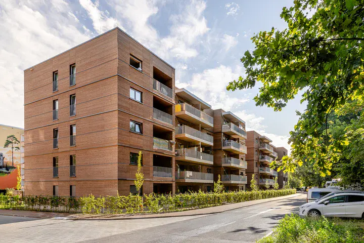 Mehrgeschossige Wohngebäude mit Balkonen und Begrünung in einem urbanen Wohnquartier.