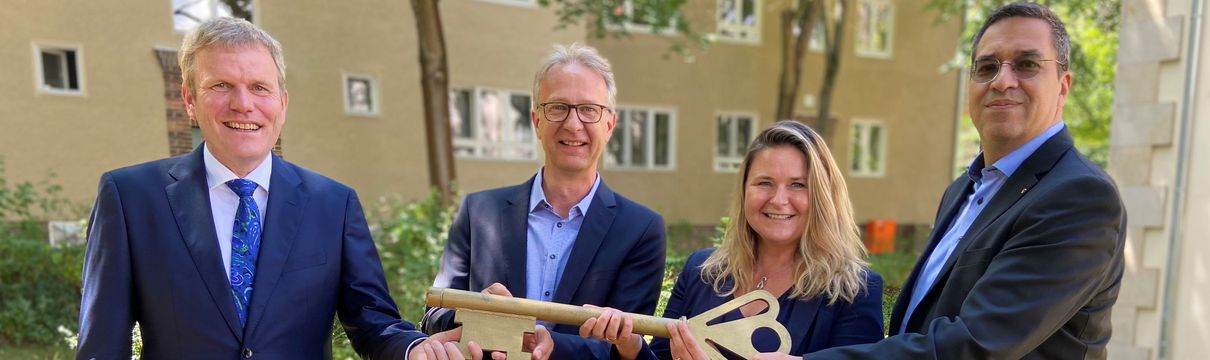 ProPotsdam Schlüsselübergabe (c) Jessica Beulshausen Der der Geschäftsführer ProPotsdam, die Bereichsleiterin des Bestandsmanagements der ProPotsdam sowie Vertreter des Deutschen GeoForschungsZentrums und des GFZ stehen in einer Reihe und halten einen symbolischen Schlüssel hoch.