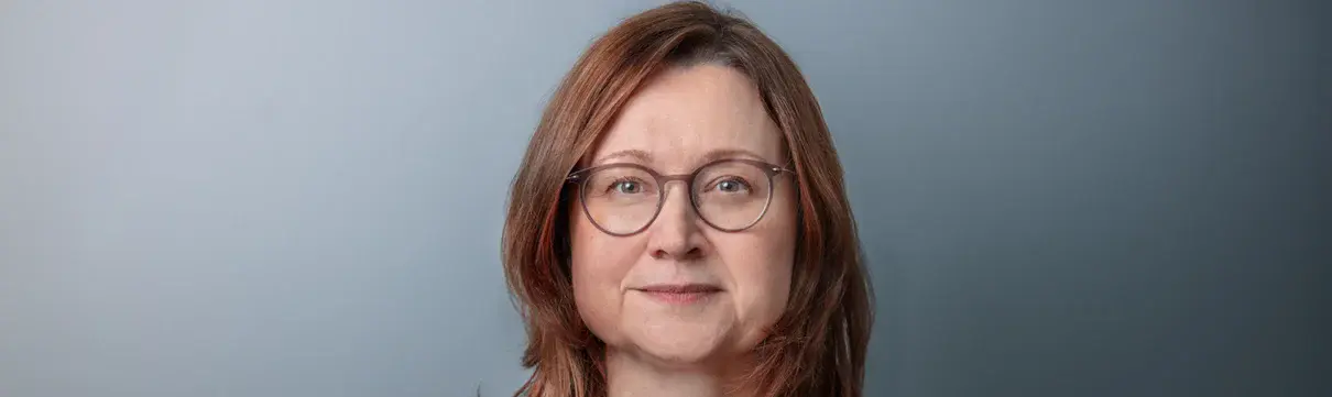 Portrait von Sandra Jacob, Geschäftsführerin Luftschiffhafen Potsdam GmbH, vor graublauem Hintergrund.
