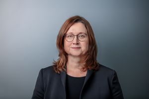 Portrait von Sandra Jacob, Geschäftsführerin Luftschiffhafen Potsdam GmbH, vor graublauem Hintergrund.