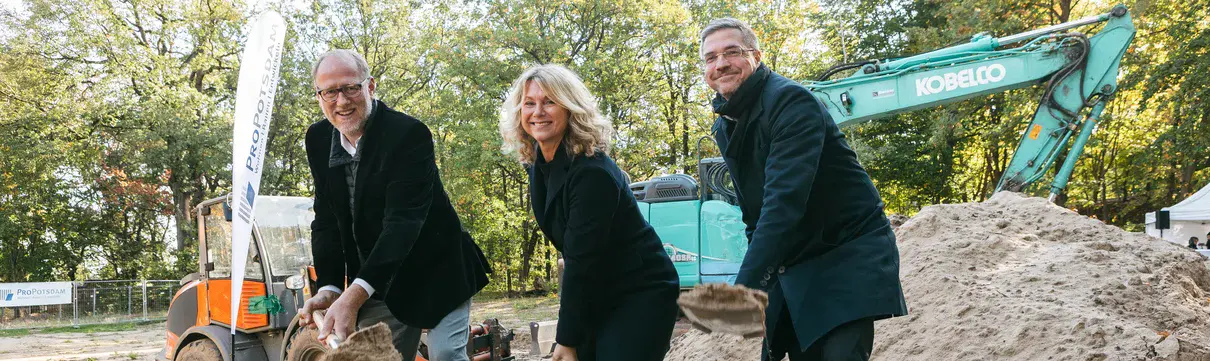 20241016_Spatenstich für Schulersatzbau an der Pirschheide_Foto Konstantin Börner Das Foto zeigt drei Personen, zwei männliche und eine weibliche, die einen Spaten in der Hand halten