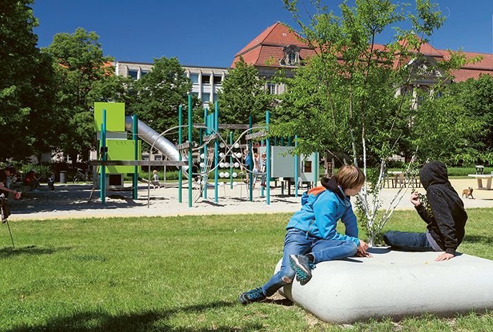 Ein Spielplatz mit vielen Klettermöglichkeiten und zwei Kinder, die im Vordergrund sitzen