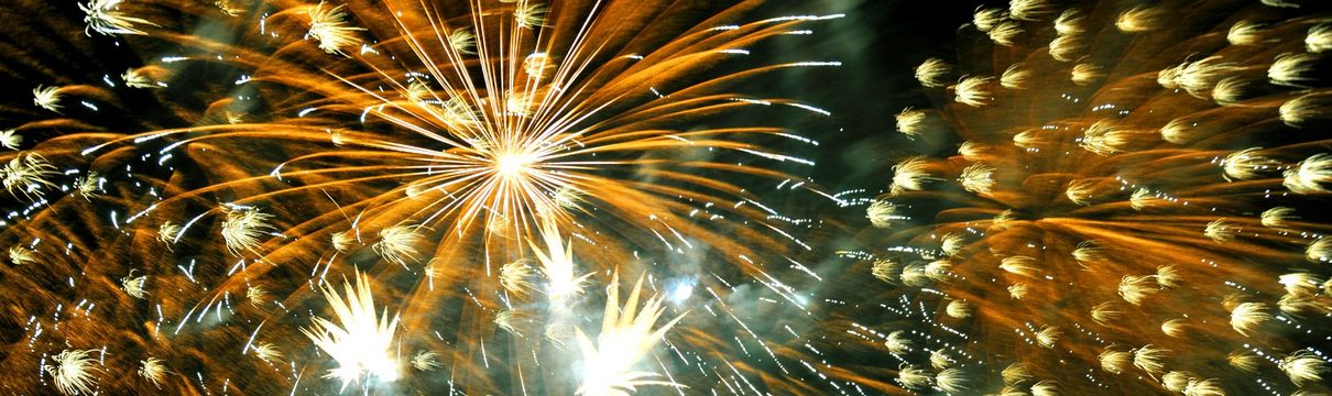 Bunte Feuerwerksexplosionen und Menschen, die in den Himmel schauen.