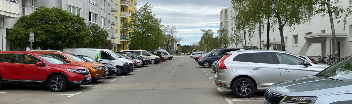Straßenansicht mit Parkplätzen auf beiden Seiten.