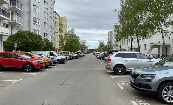 Straßenansicht mit Parkplätzen auf beiden Seiten.