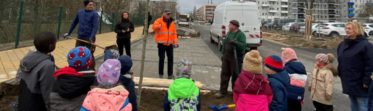 Mehrere Kinder die am Straßenrand einen Baum einpflanzen.