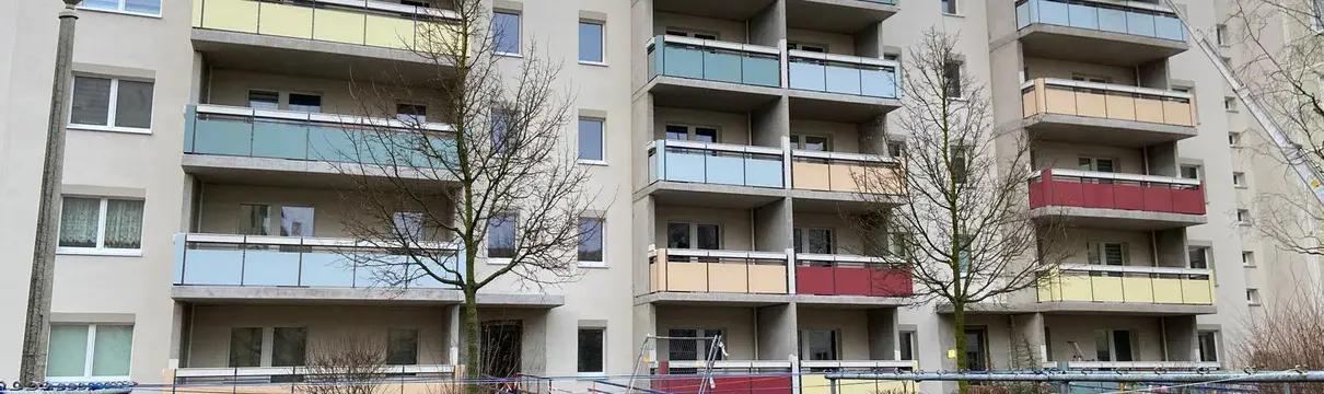 Wohngebäude mit Balkonen und grüner Wiese im Vordergrund.