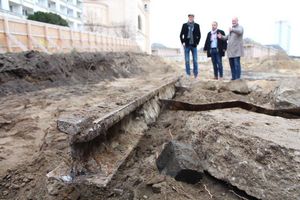 Der Geschäftsführer der ProPotsdam und der Bauderzernent stehen zusammen mit einem dritten Mann oder einer von Sand bedeckten, rostik wirkendem Gleis.