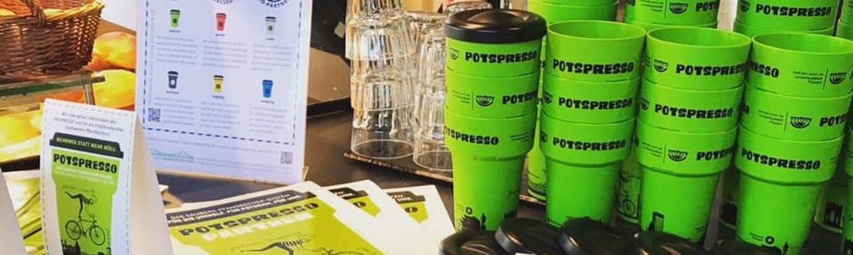 Zu sehen sind PotsPRESSO-Kaffeebecher, Flyer und Gläser.