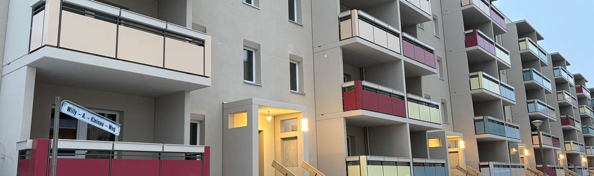 Sanierter Wohnblock im Willy-A.-Kleinau-Weg im Winter mit neuen Balkonen und farbigen Brüstungen; Eingangsbereiche beleuchtet, Bauarbeiten im Außenbereich noch nicht abgeschlossen.