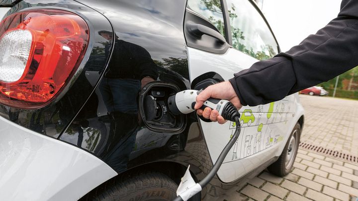 Hand die ein eAuto mit Strom betankt