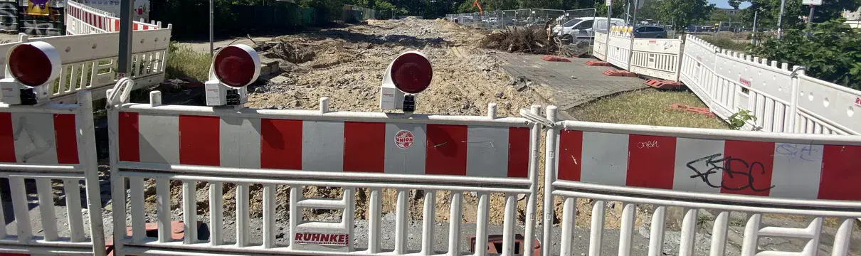 Rotweiße Absperrgitter zur Straßensperrungen, mit dahinterliegendem Bauschutt. 