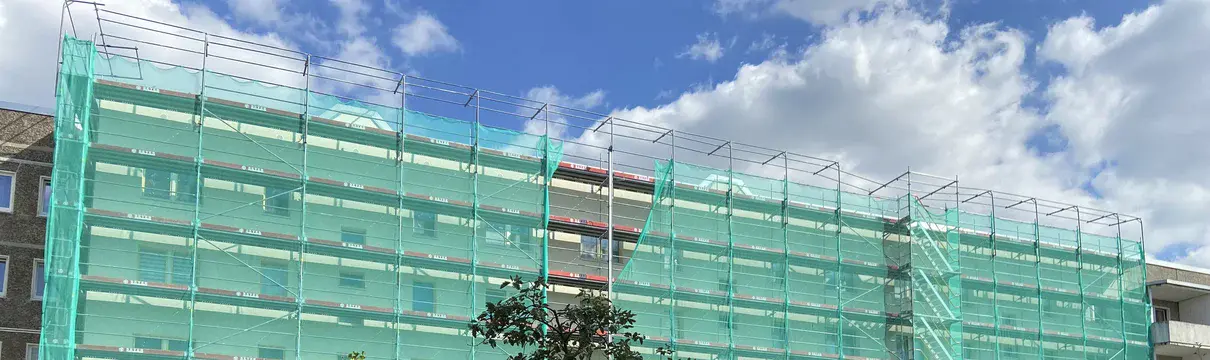 Straßenansicht eines Gebäudes mit grünen Baugerüsten