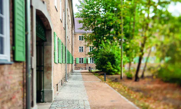 helle Backsteine und grüne Fensterläden sowie hoher Baumbewuchs zeigen den Charme der sanierten Altbausiedlung