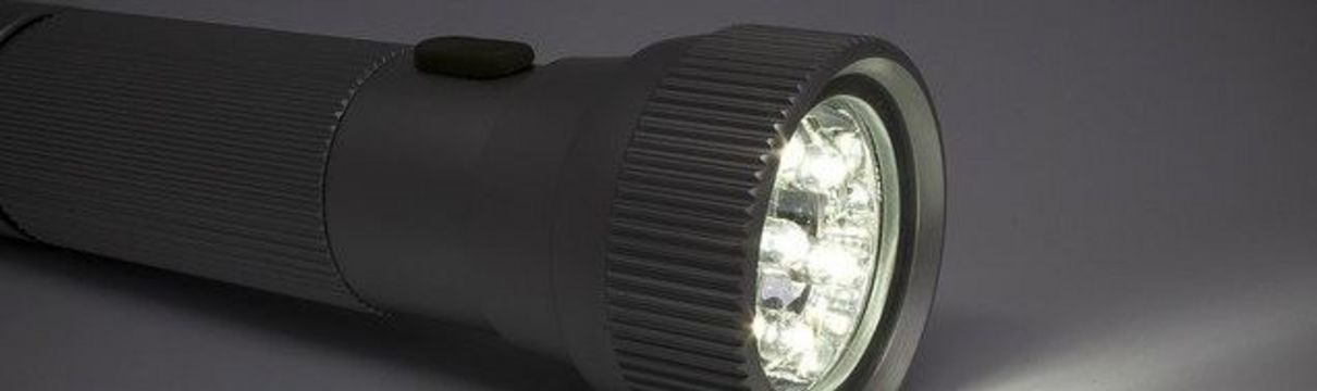 Zu sehen ist eine angeschaltete Taschenlampe vor grauem Hintergrund
