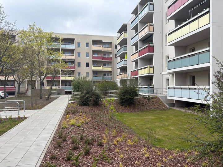Sanierte Wohnanlage mit begrüntem Innenhof Modernisierte Mehrfamilienhäuser mit farbigen Balkonen, begrüntem Innenhof und barrierefreien Wegen